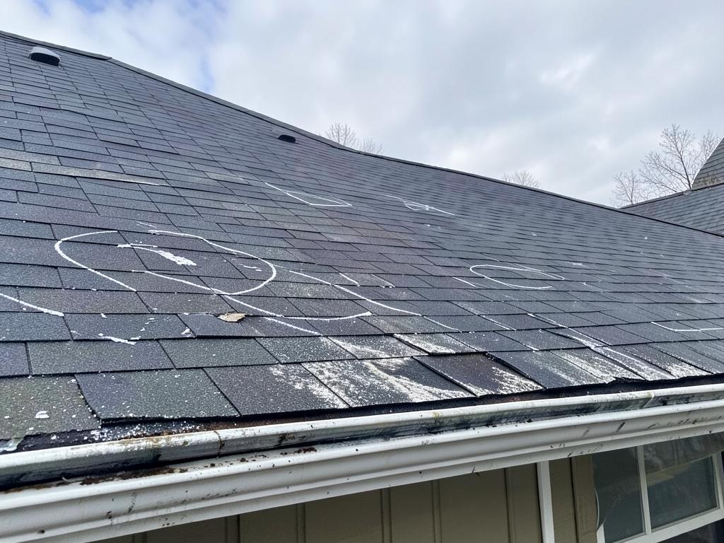 Hail damage marked on a shingle roof for an insurance claim