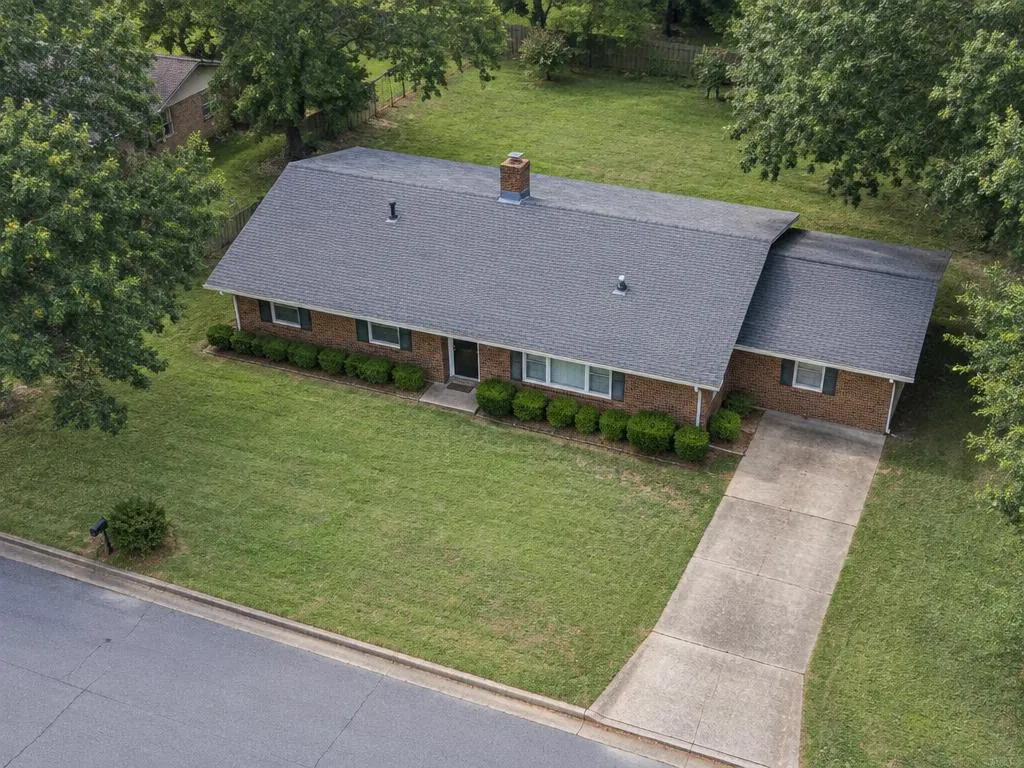 AI aerial illustration of a modest brick ranch with a low-pitch gray shingle roof
